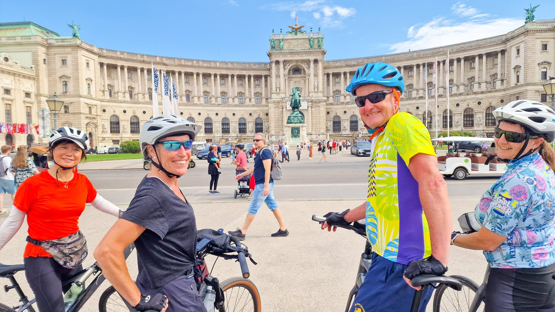 Group of cyclists smiling in front of Vienna’s Hofburg Palace during a guided city cycling tour