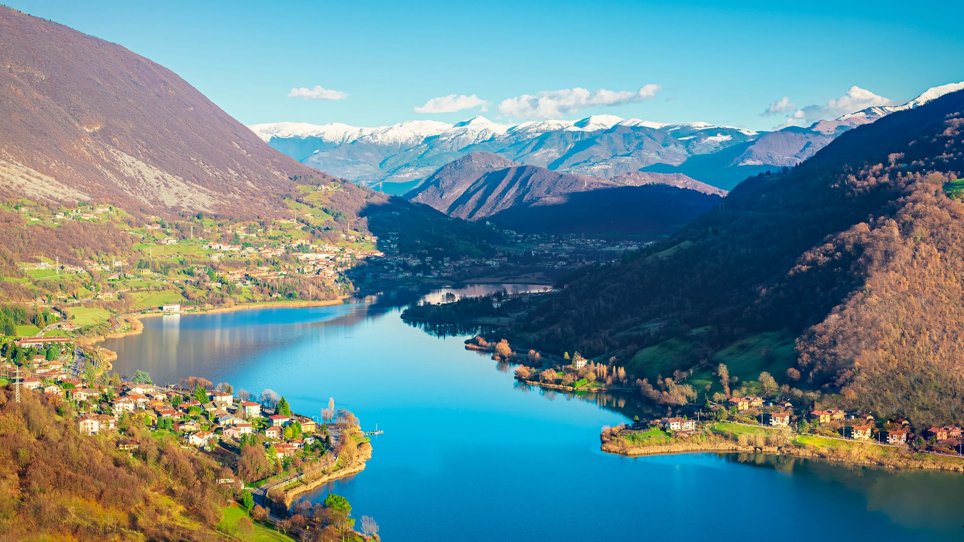 A panoramic view of Lake Endine by green hills and distant snow-capped mountains