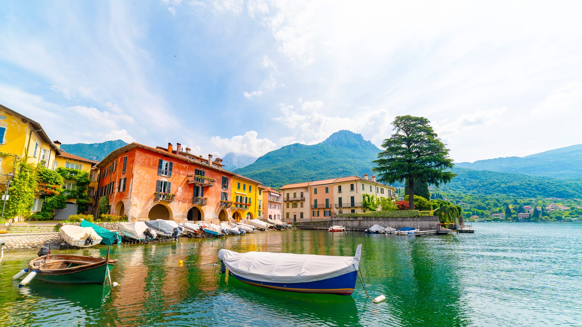 Waterfront of Varenna on Lake Como, with colorful buildings and small boats against a mountain backdrop