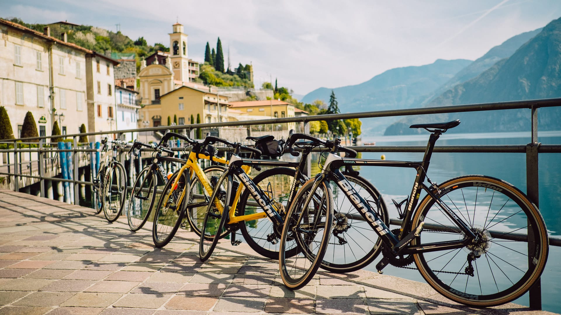 Row of bicycles parked along a lakeside promenade with historic buildings and mountains in the background at Lake Iseo