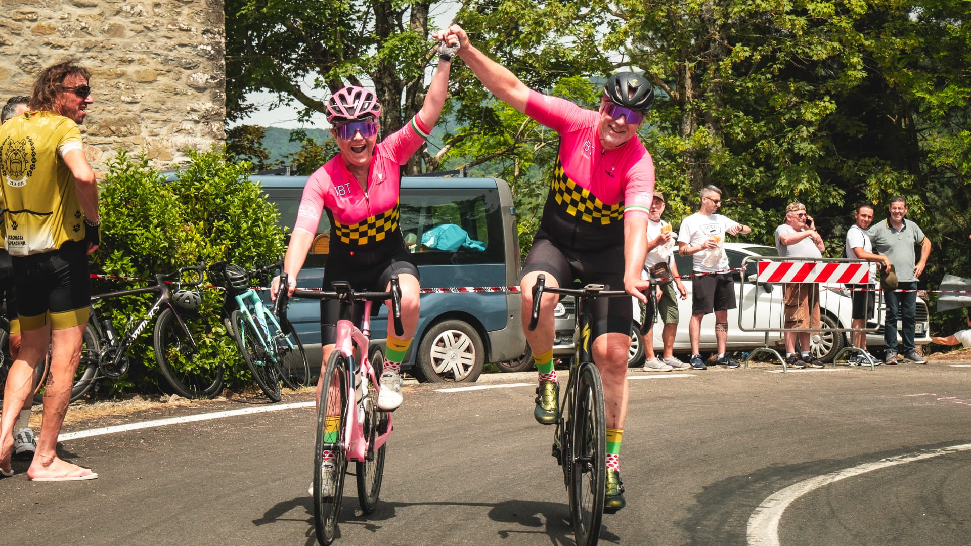 Two cyclists holding hands and celebrating as they cross a road section during a ride