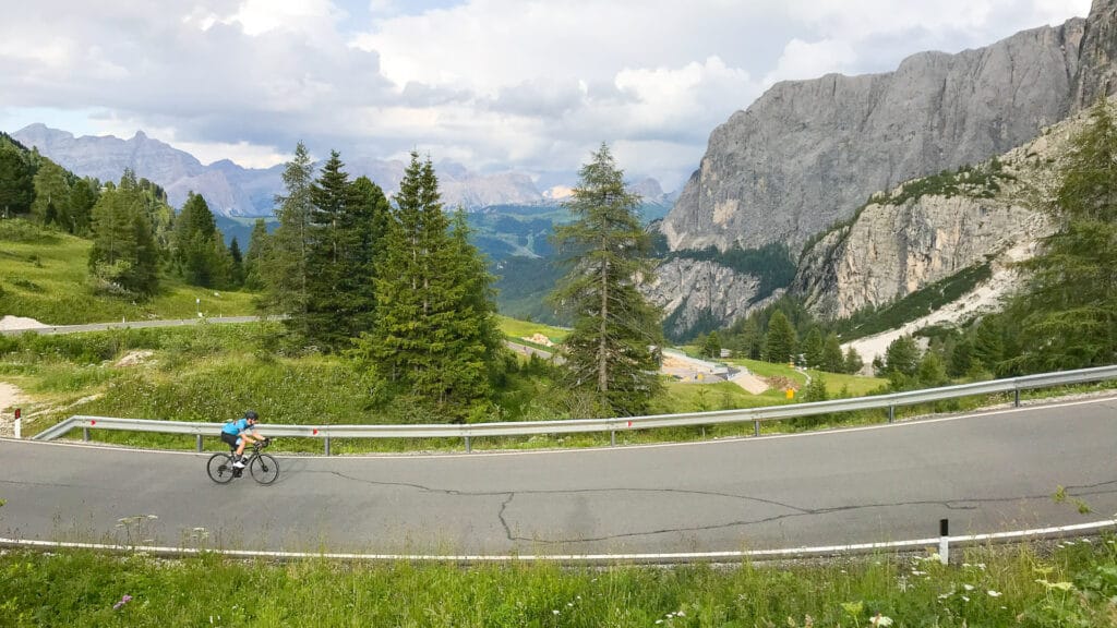 Cyclist climbing a winding mountain road on Passo Gardena in the Dolomites