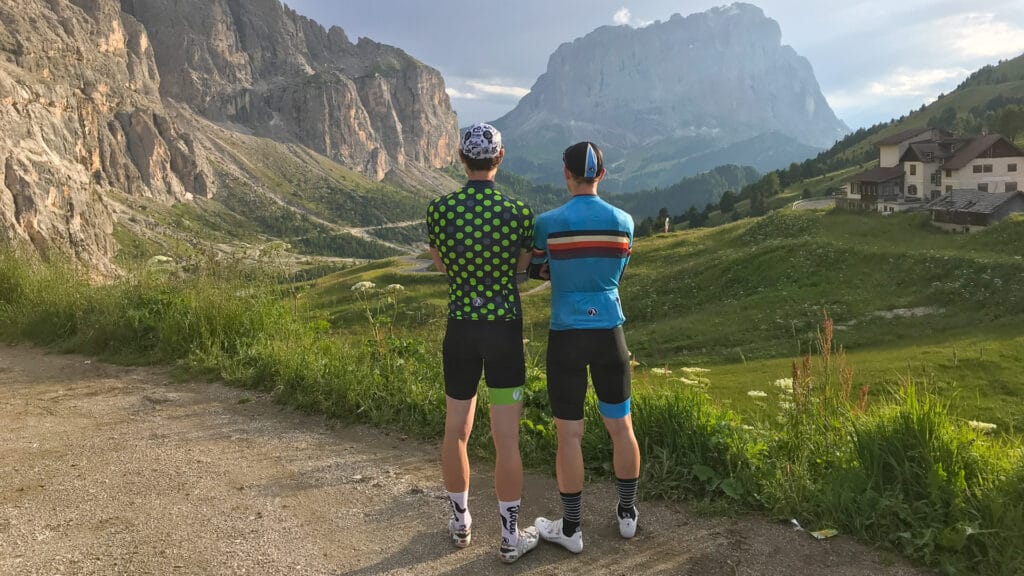 Two cyclists overlooking mountain scenery on Passo Gardena in the Dolomites