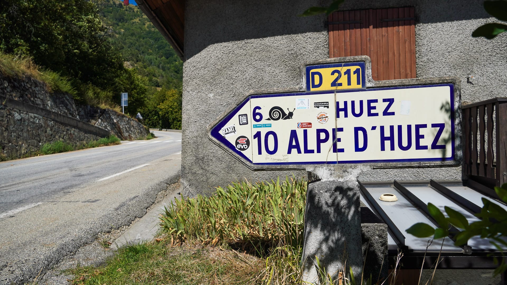 Road sign pointing towards Alpe d’Huez on a sunny mountain road in France
