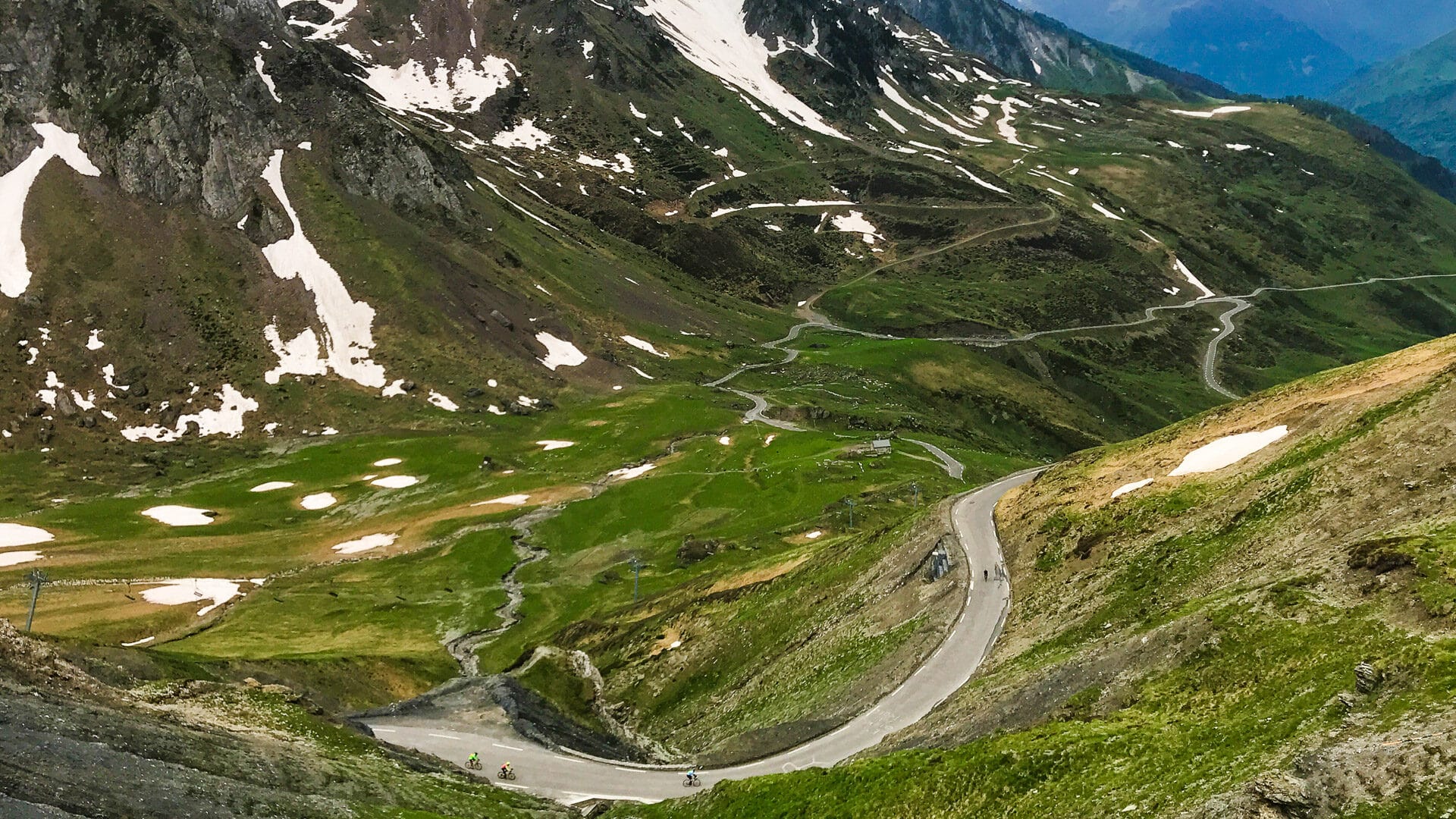 Cyclists on a mountain pass surrounded by alpine scenery in France