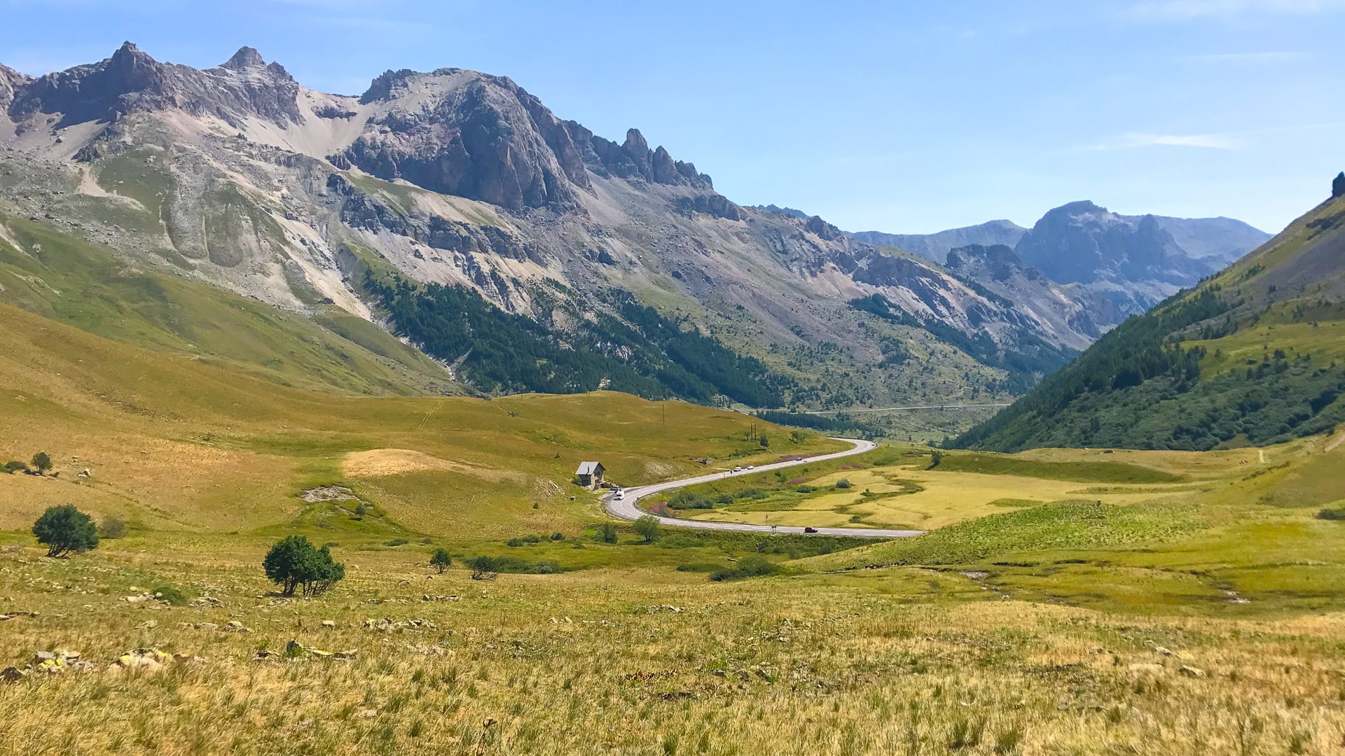 Scenic alpine valley road winding through meadows and mountains in Col de Lauteret, near the Col de Galibier
