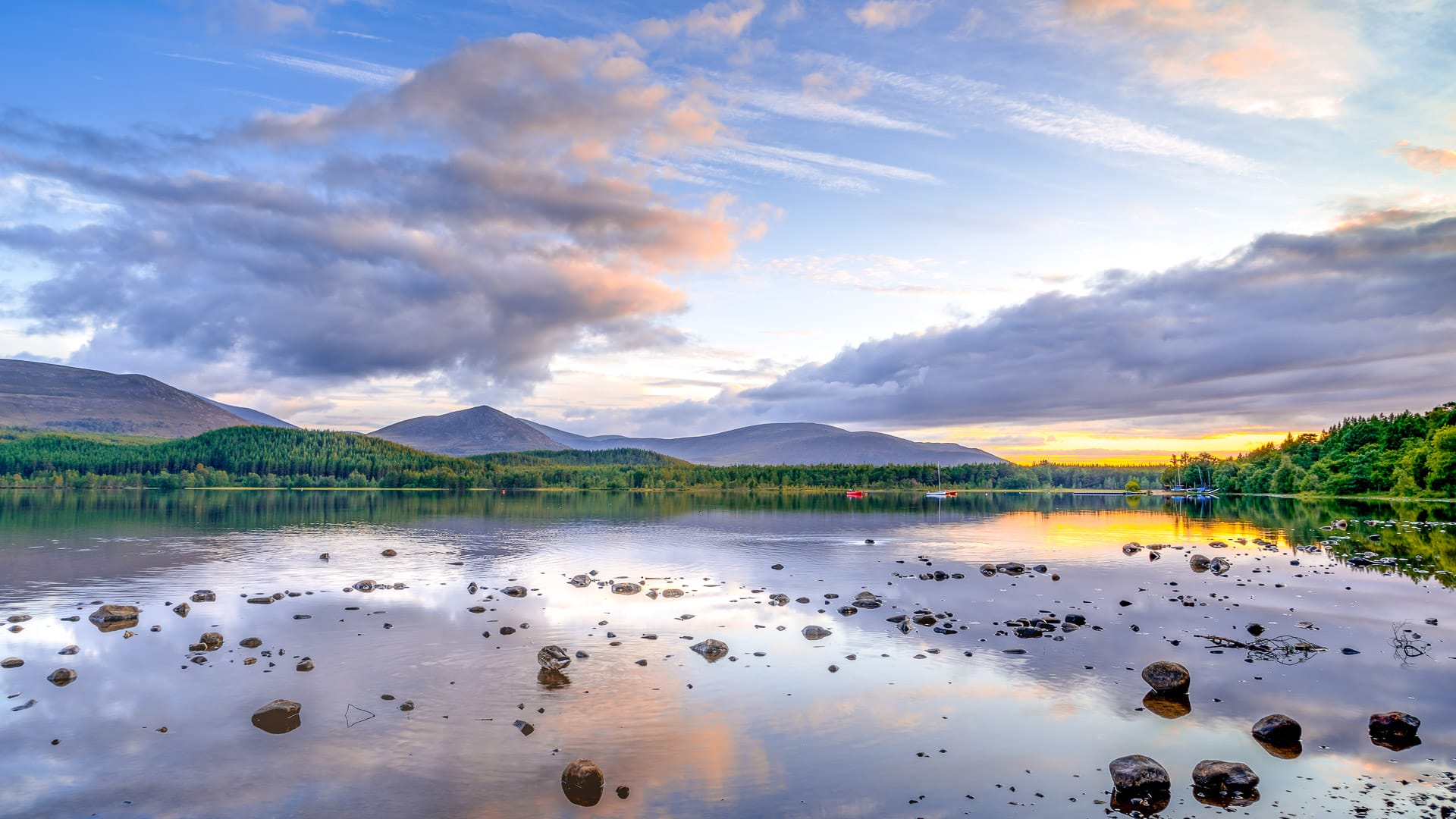 Sunset over Loch Morlich with clouds and hills reflected in the water