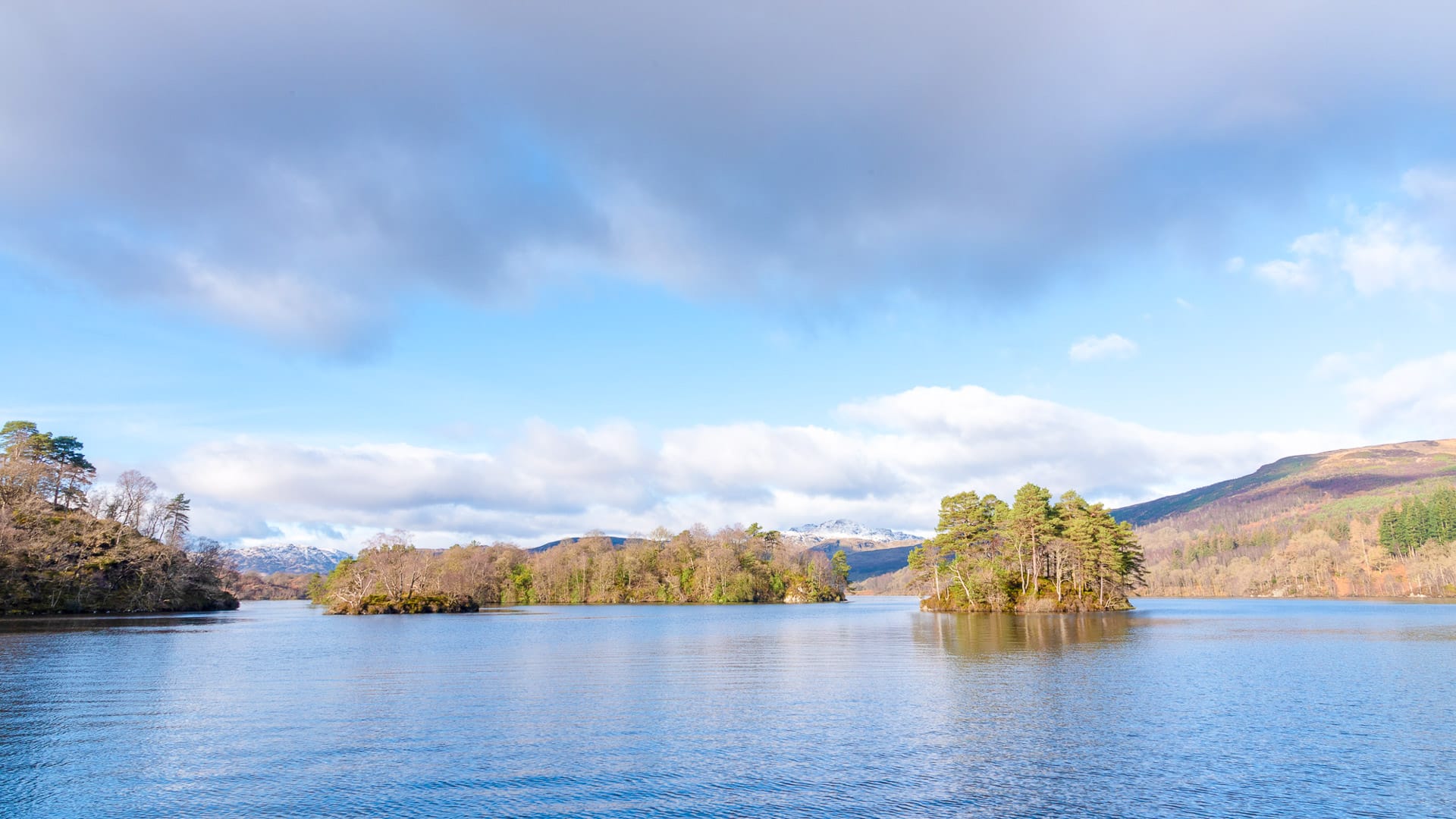 Small forested islands on Loch Lomond under a dramatic sky