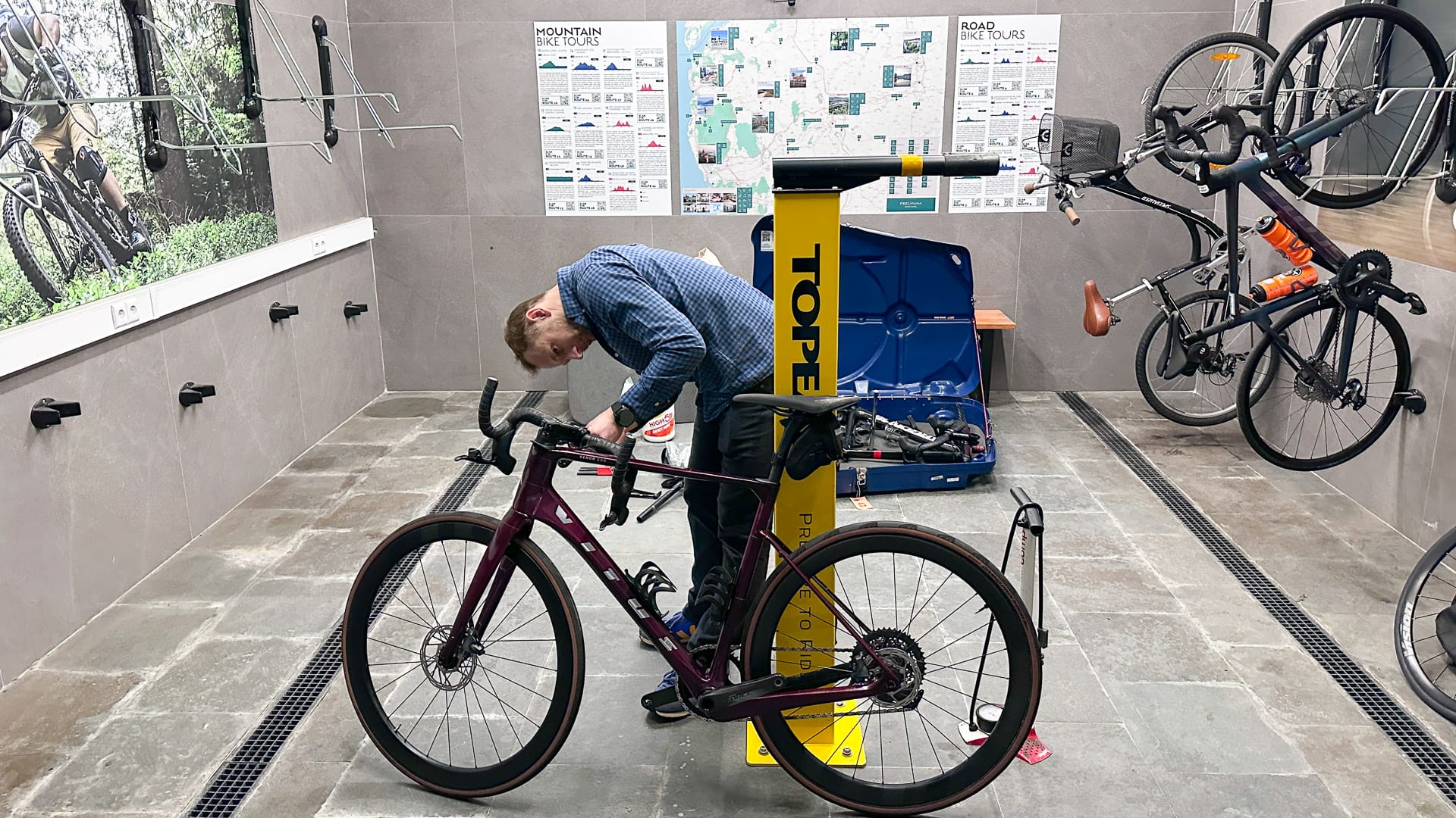 Bike hotel workshop with Topeak service stand where a young rider adjusts his road bike