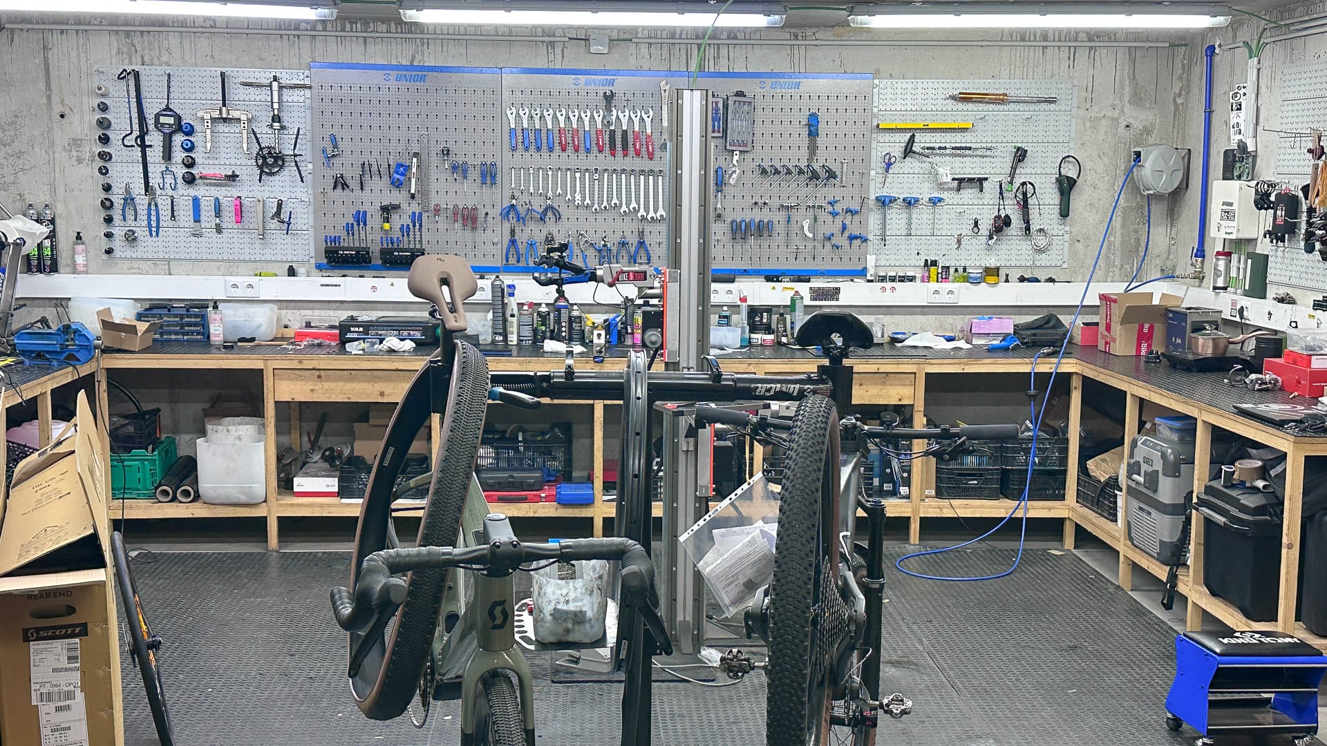Bike hotel professional workshop with two bikes in workstands surrounded by benches and wall-mounted tools
