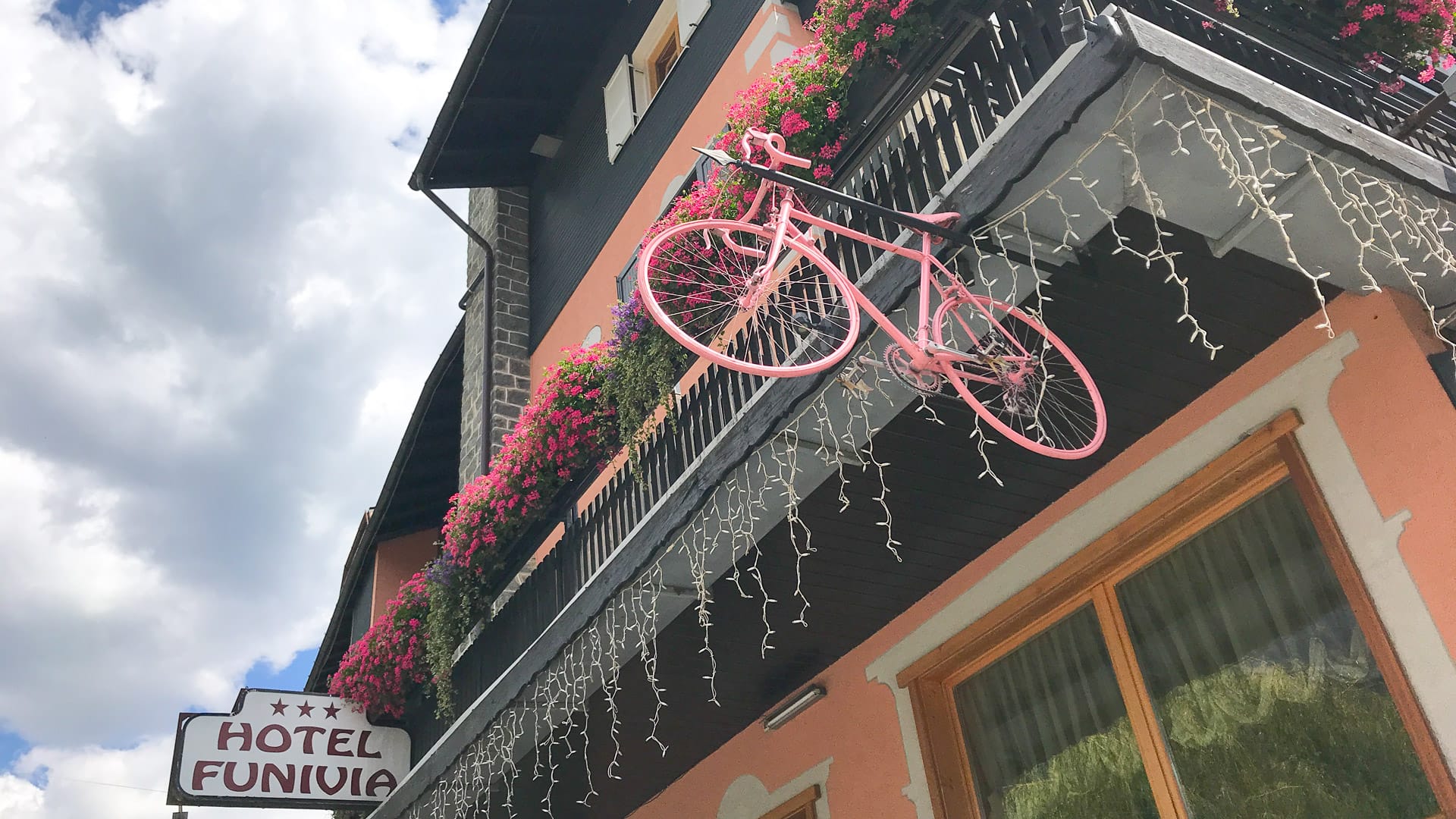 A pink color cycle hangs on outside in bike hotels