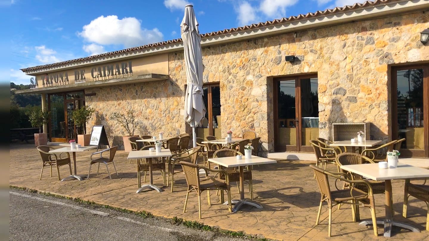 Stone café terrace with tables and mountain views at Sa Tafona, Caimari