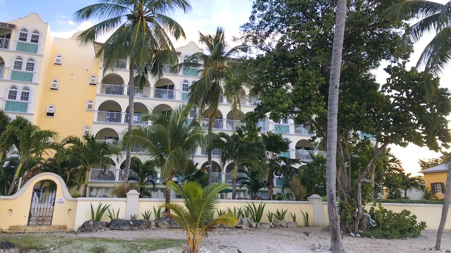 Beachfront hotel in Barbados with palm trees and balconies overlooking the sea