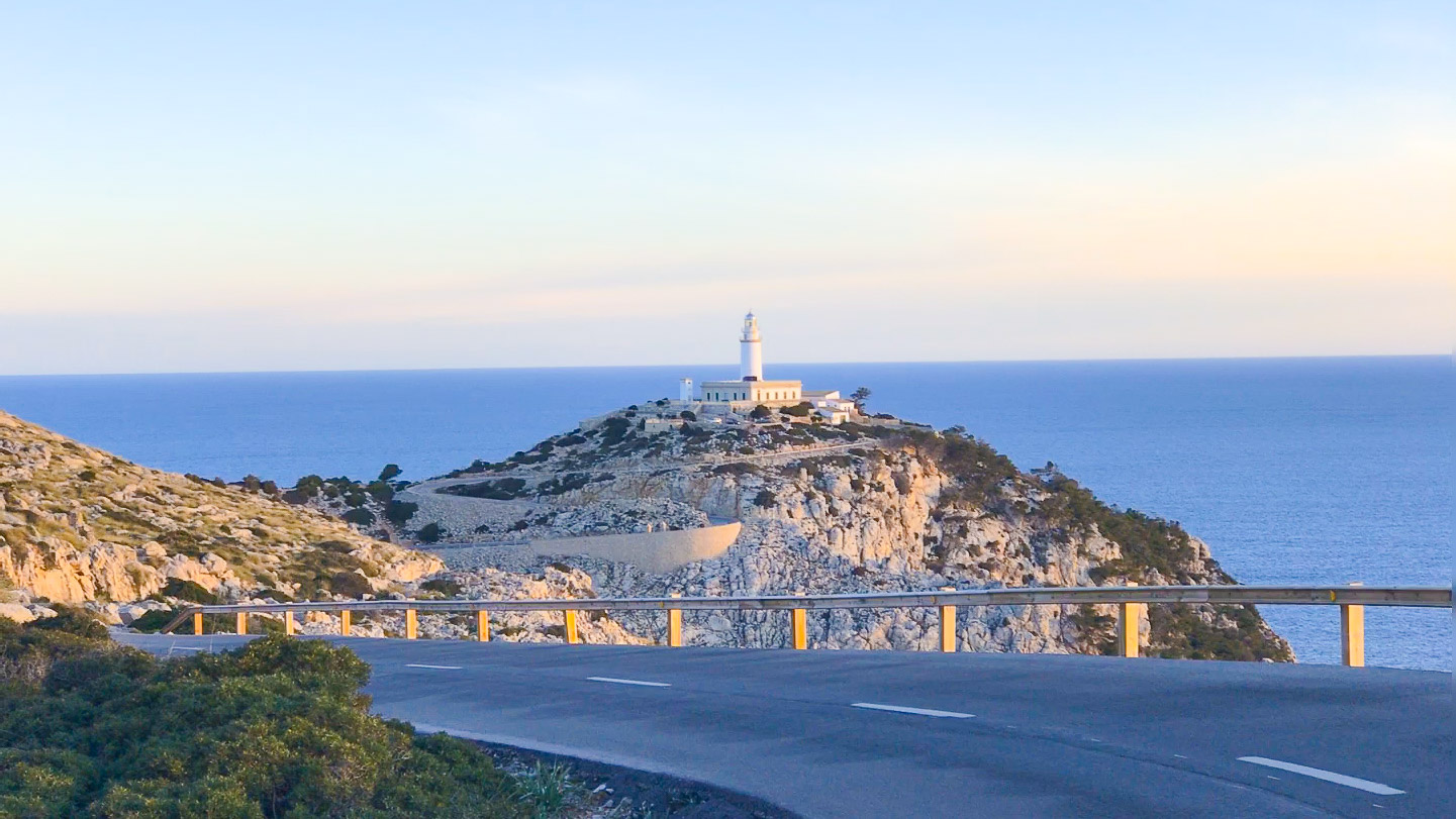 Coastal road curving towards the Cap de Formentor lighthouse above deep blue sea, Mallorca