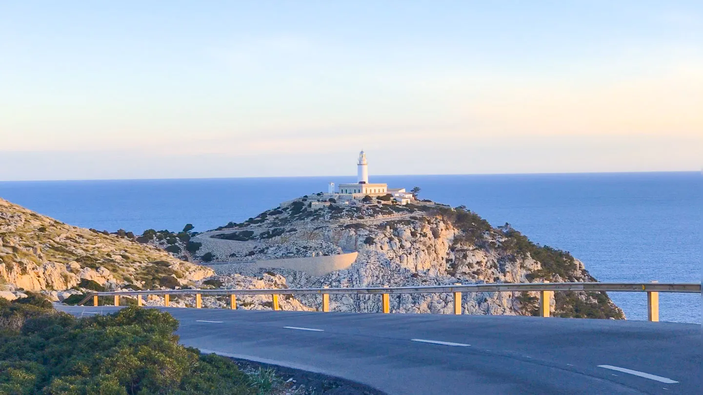 Coastal road curving towards the Cap de Formentor lighthouse above deep blue sea, Mallorca