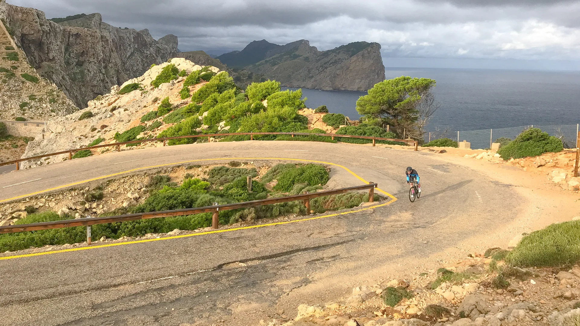 Cyclist on the cap de formentor cycling route, Mallorca, approaching the lighthouse