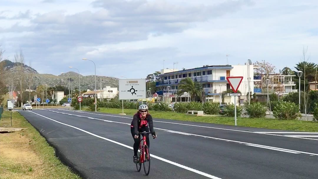 Cyclist riding on smooth open road near Pollença with mountain backdrop in Mallorca