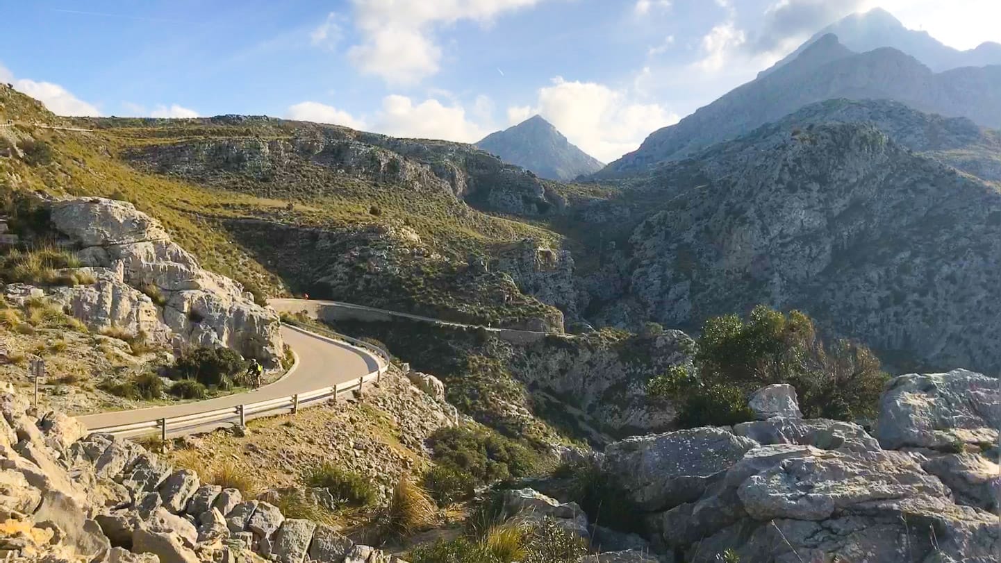 Rugged mountain road winding through rocky terrain in Mallorca’s Serra de Tramuntana, with dramatic peaks and hazy light