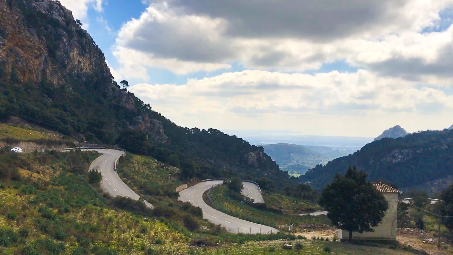 Winding road climbing through Serra de Tramuntana near Coll de Sóller, Mallorca, with mountain backdrop and open valley views