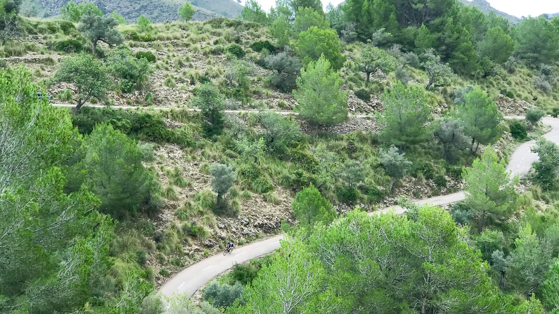 Cyclist on long switchback on road back to Arta from Ermita de Betlem monastery