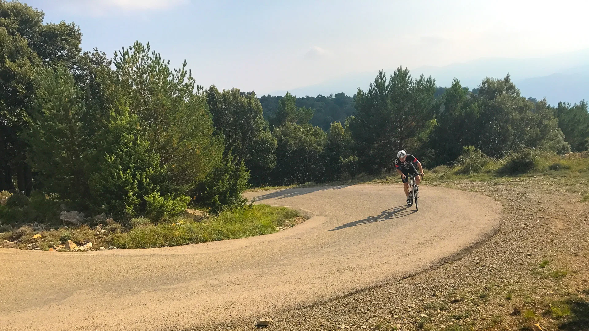 Cyclist ascending a hairpin bend on the Mare de Déu del Mont climb near Girona