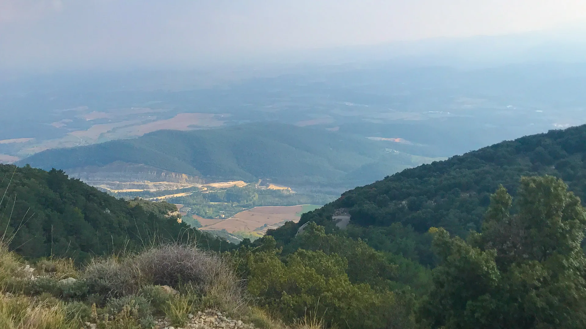 Panoramic view across forested hills from the Mare de Déu del Mont summit