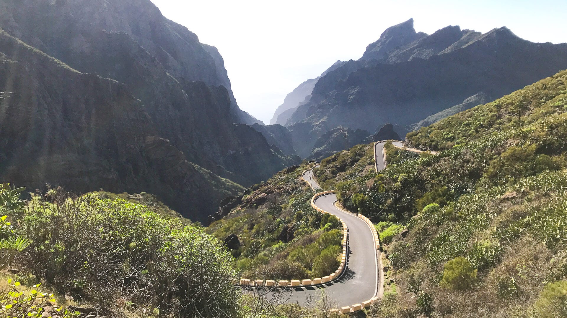 Winding mountain road descending into the Masca Gorge in Tenerife with steep cliffs and lush vegetation