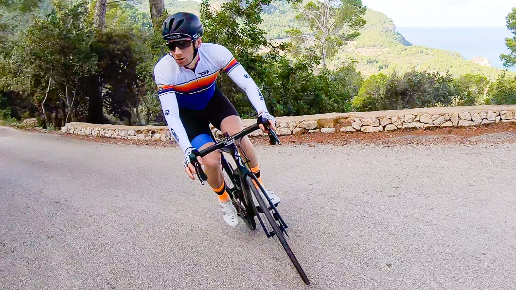 Cyclist rounding corner on coastal mountain road near Port des Canonge, Mallorca