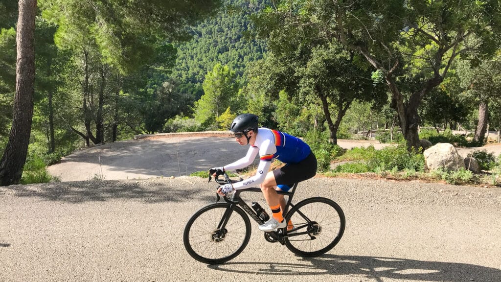 Close-up of cyclist climbing forested switchback road above Port des Canonge, Mallorca