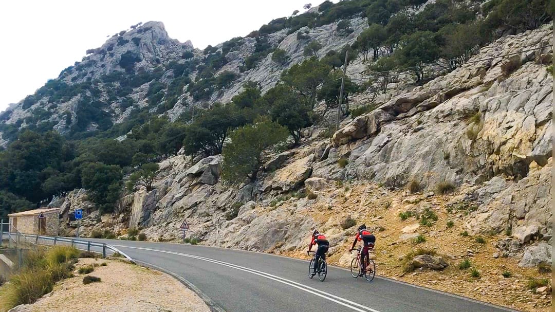 Cyclists climbing Puig Major, the highest peak in Mallorca, with scenic mountainous backdrop
