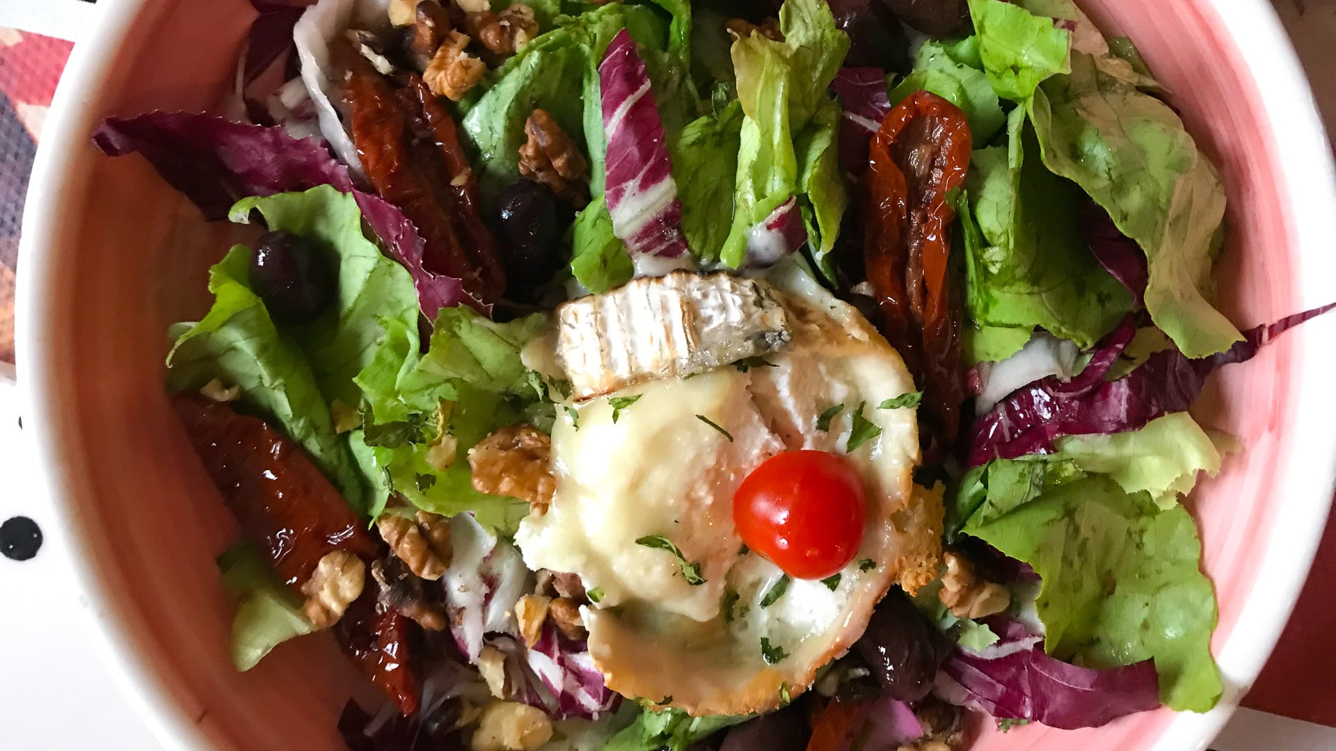 Colourful goat’s cheese salad with mixed leaves, sun-dried tomatoes, walnuts, black olives and a cherry tomato garnish