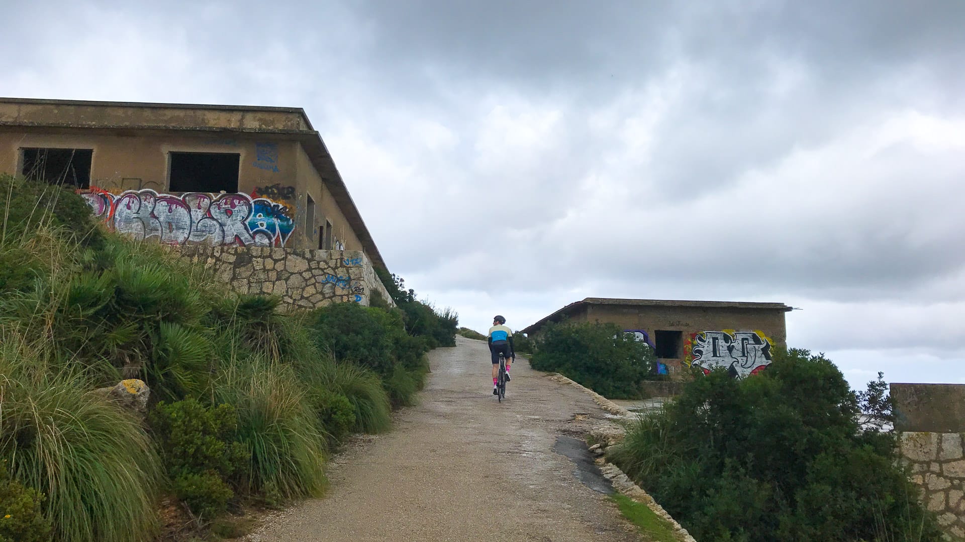 Cycling through abandoned buildings on the way up Talaia d'Albercutx climb Mallorca