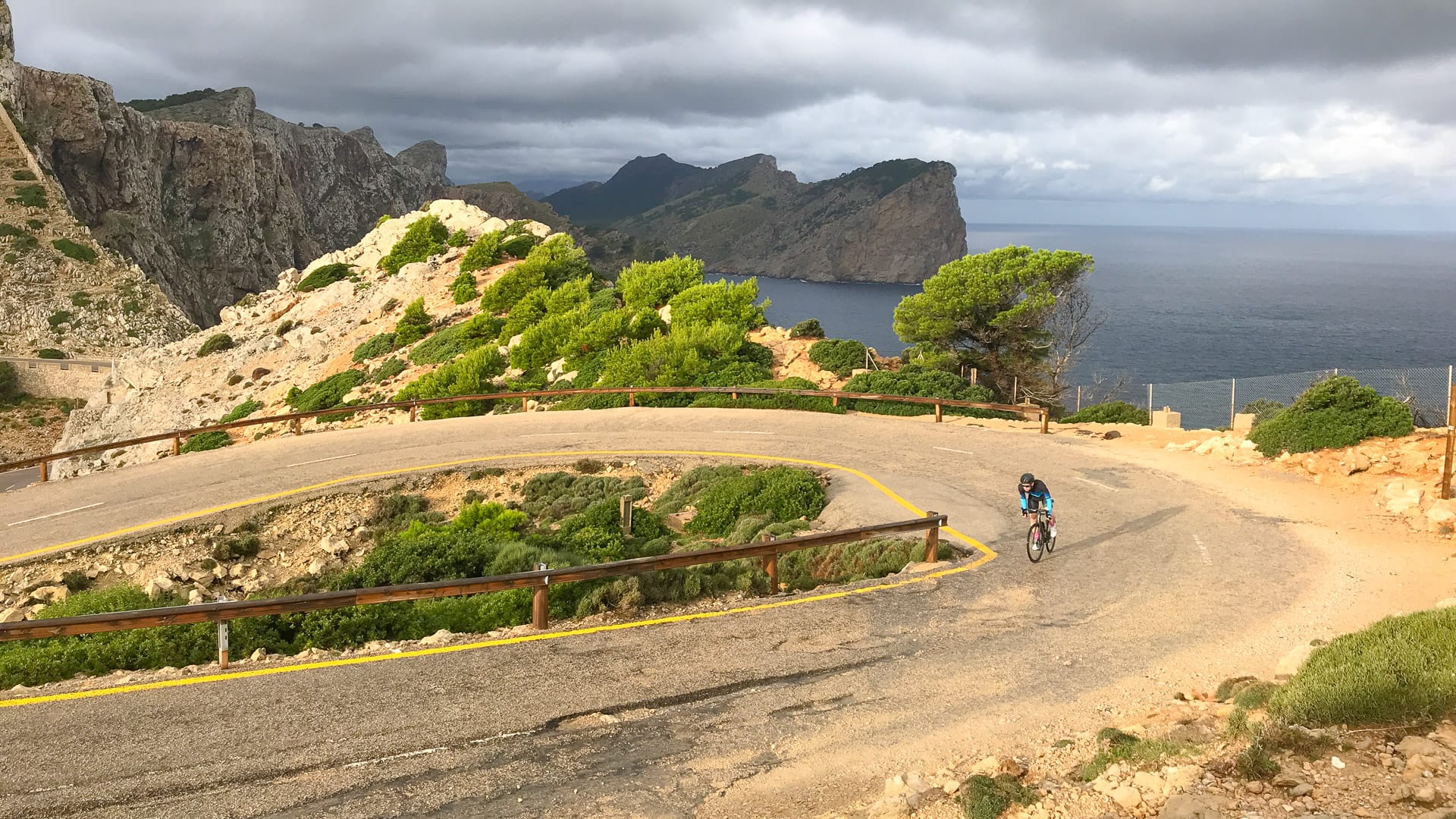 Cyclist on the cap de formentor cycling route, Mallorca, approaching the lighthouse
