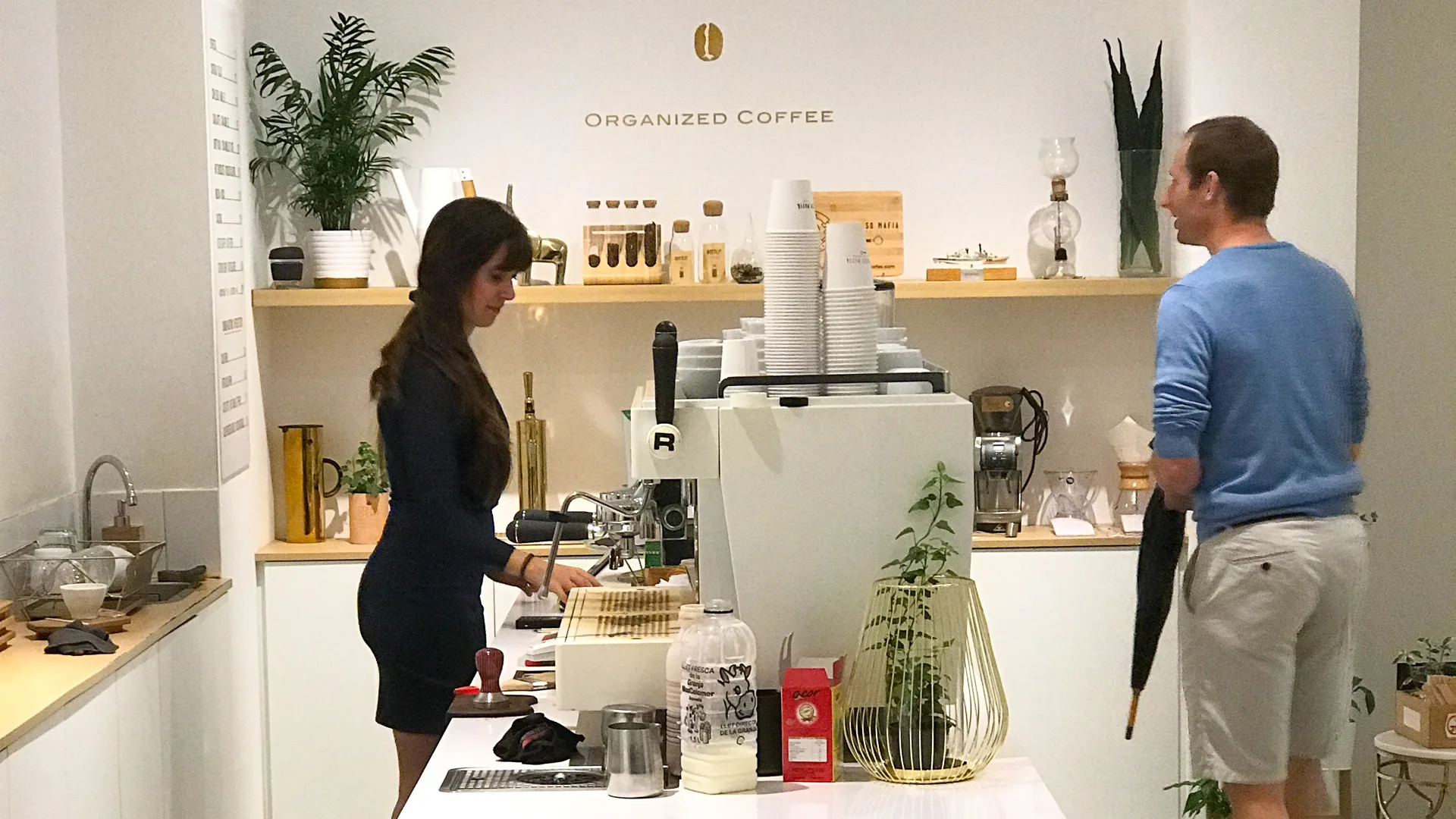 Barista preparing drinks at Espresso Mafia in Girona with clean white decor and modern coffee setup
