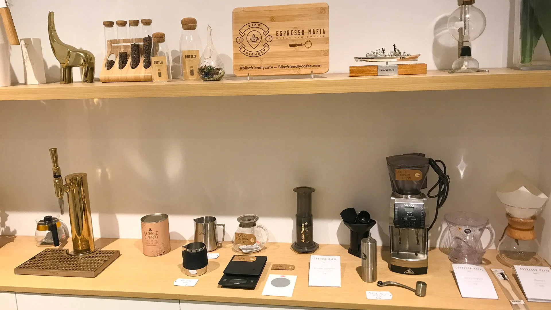 Display shelf with coffee-making gear and branded products at Espresso Mafia café in Girona