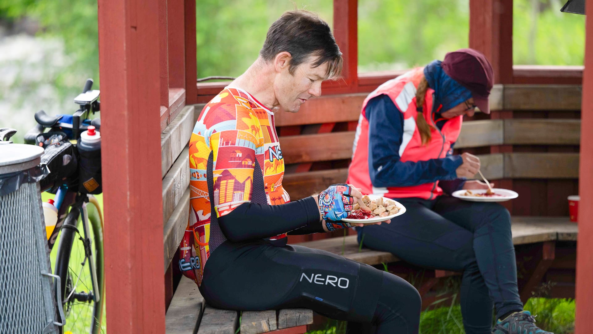 Cyclists enjoying a meal together in a wooden shelter along the MSR 2025 route in Sweden
