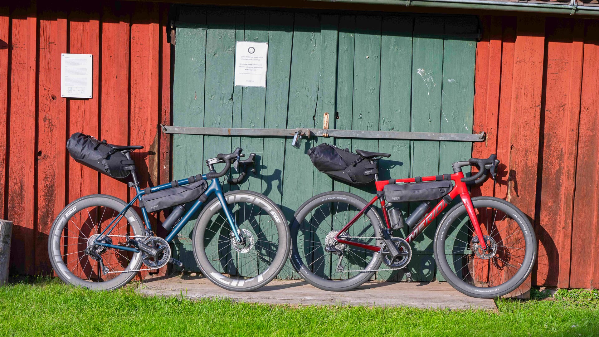 Two fully packed bikepacking bikes leaning against a red and green barn in Västerbotten, Sweden