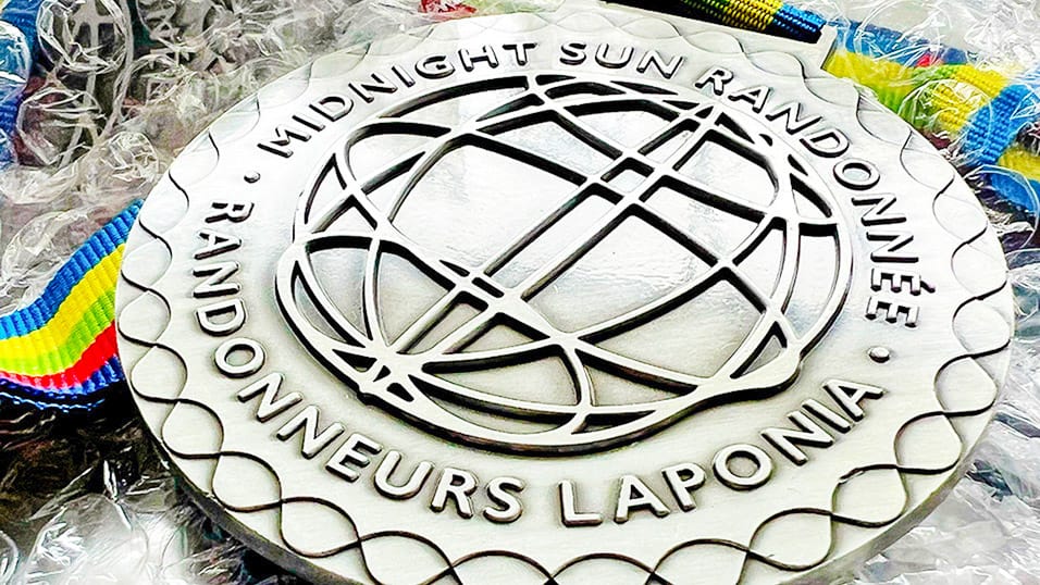 Midnight Sun Randonnée Laponia finisher medal with globe design and coloured ribbon