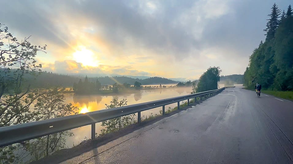 Sunrise over a misty river in northern Sweden with soft light and forested hills