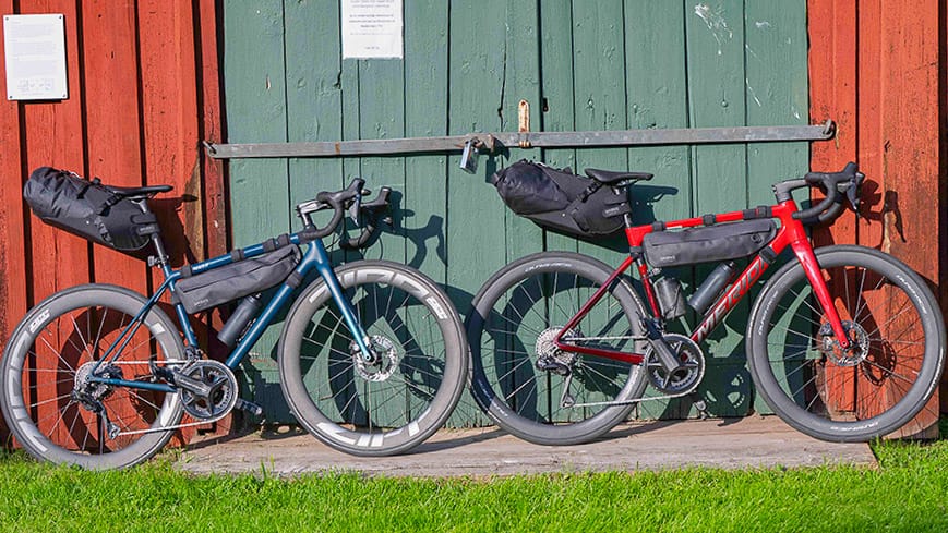 Two loaded bikepacking bikes parked against a red barn with green doors in Västerbotten Sweden