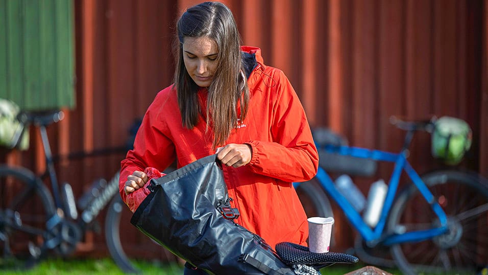 Rider in red jacket packing a handlebar bag before the Midnight Sun Randonnée in Västerbotten Sweden