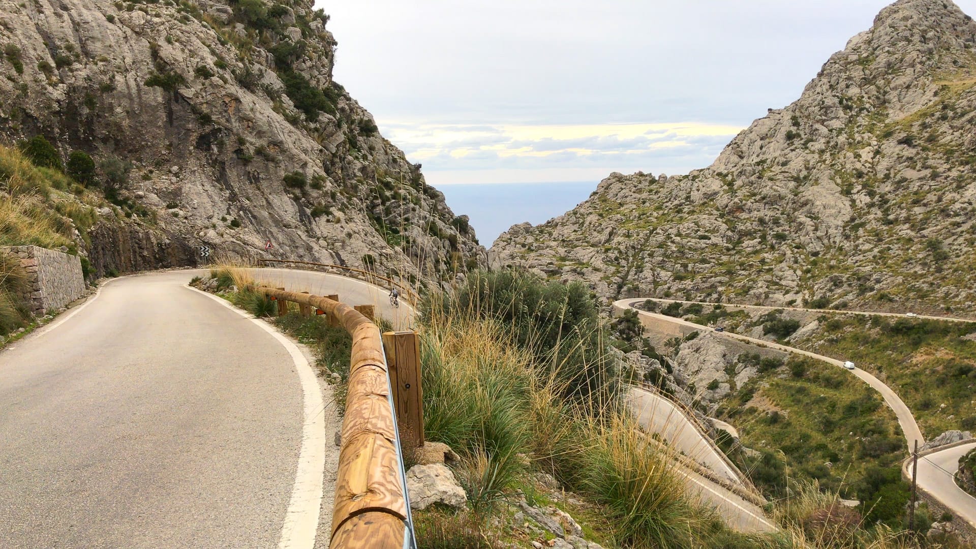Winding mountain road descending between steep limestone cliffs towards the sea on the Sa Calobra climb, Mallorca