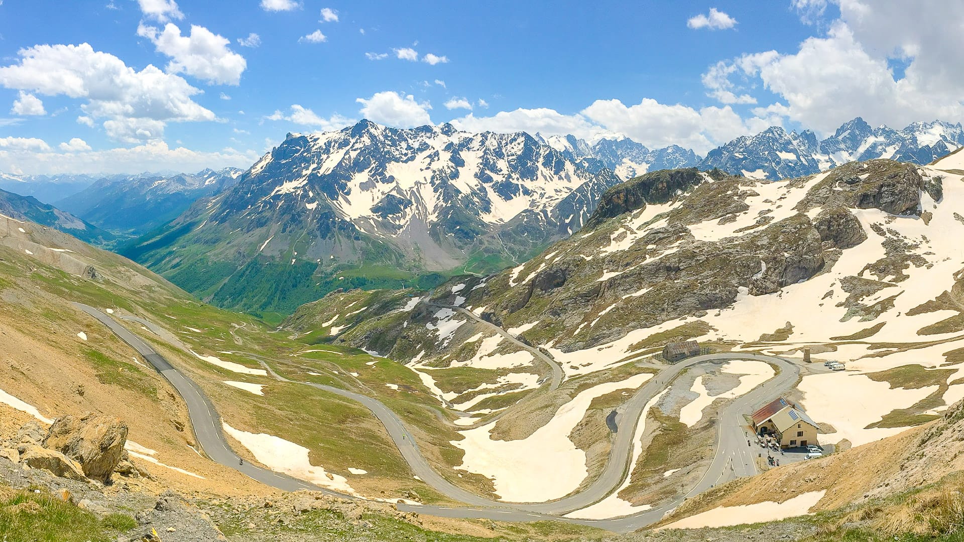 Panoramic view of snow-lined hairpin road winding through the French Alps on the Route des Grandes Alpes
