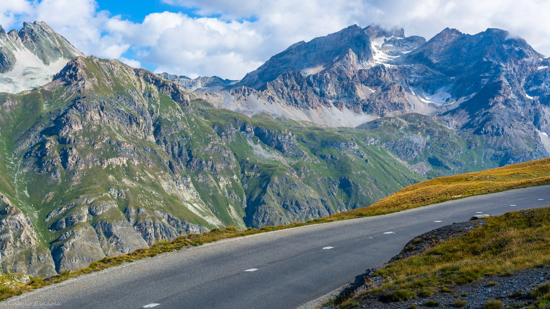 Empty alpine road curving beneath jagged mountain peaks along the Route des Grandes Alpes, France