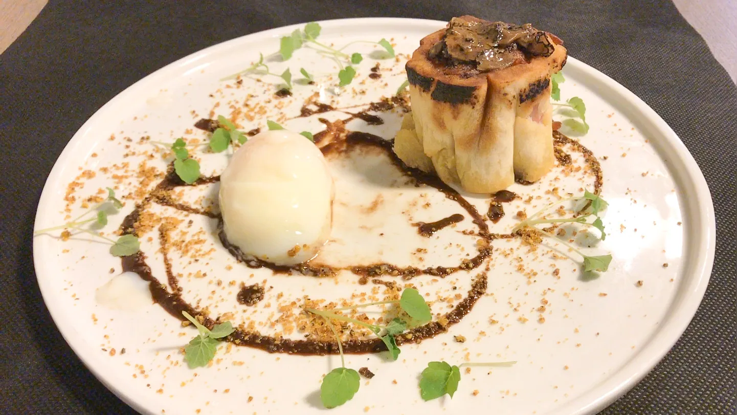 Creative gourmet dish with pastry, poached egg, microgreens and sauce at restaurant in Girona