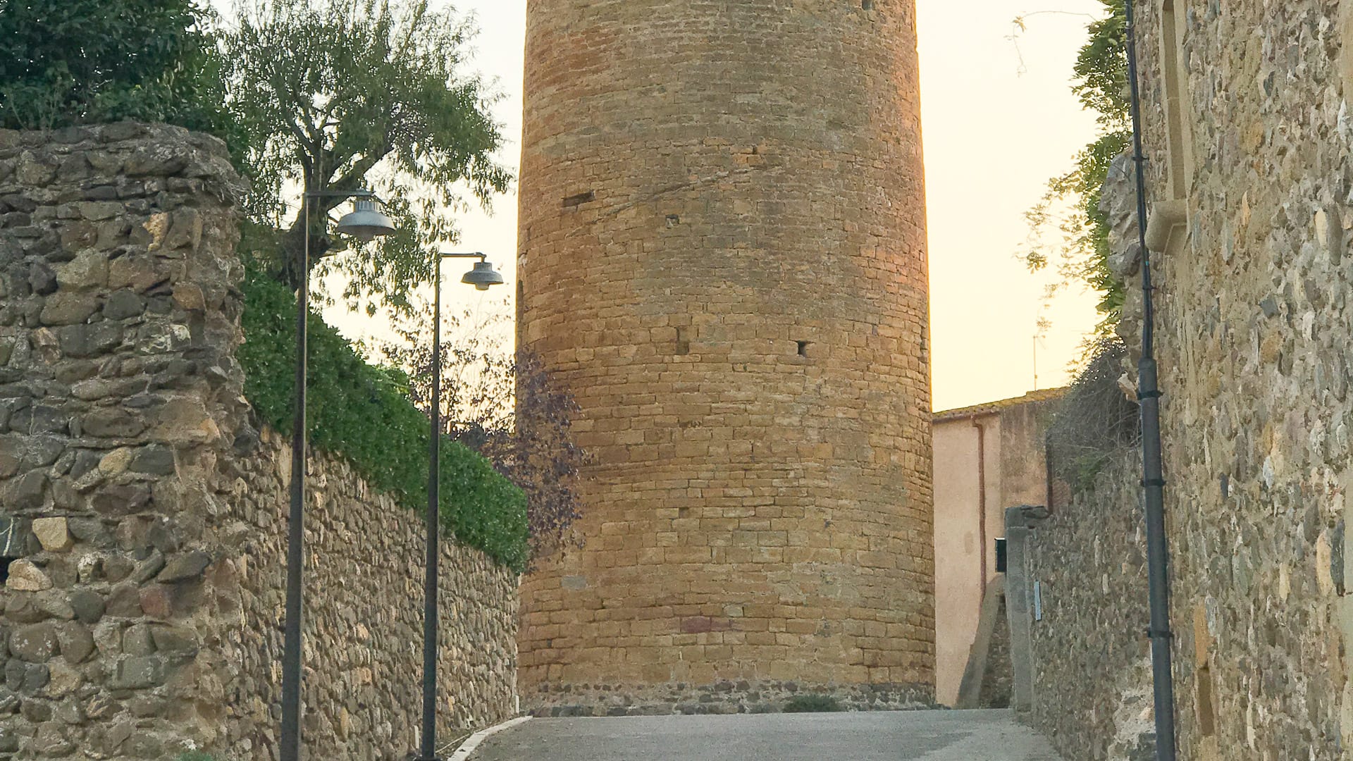 Stone watchtower along narrow walled lane at golden hour in Girona, Spain