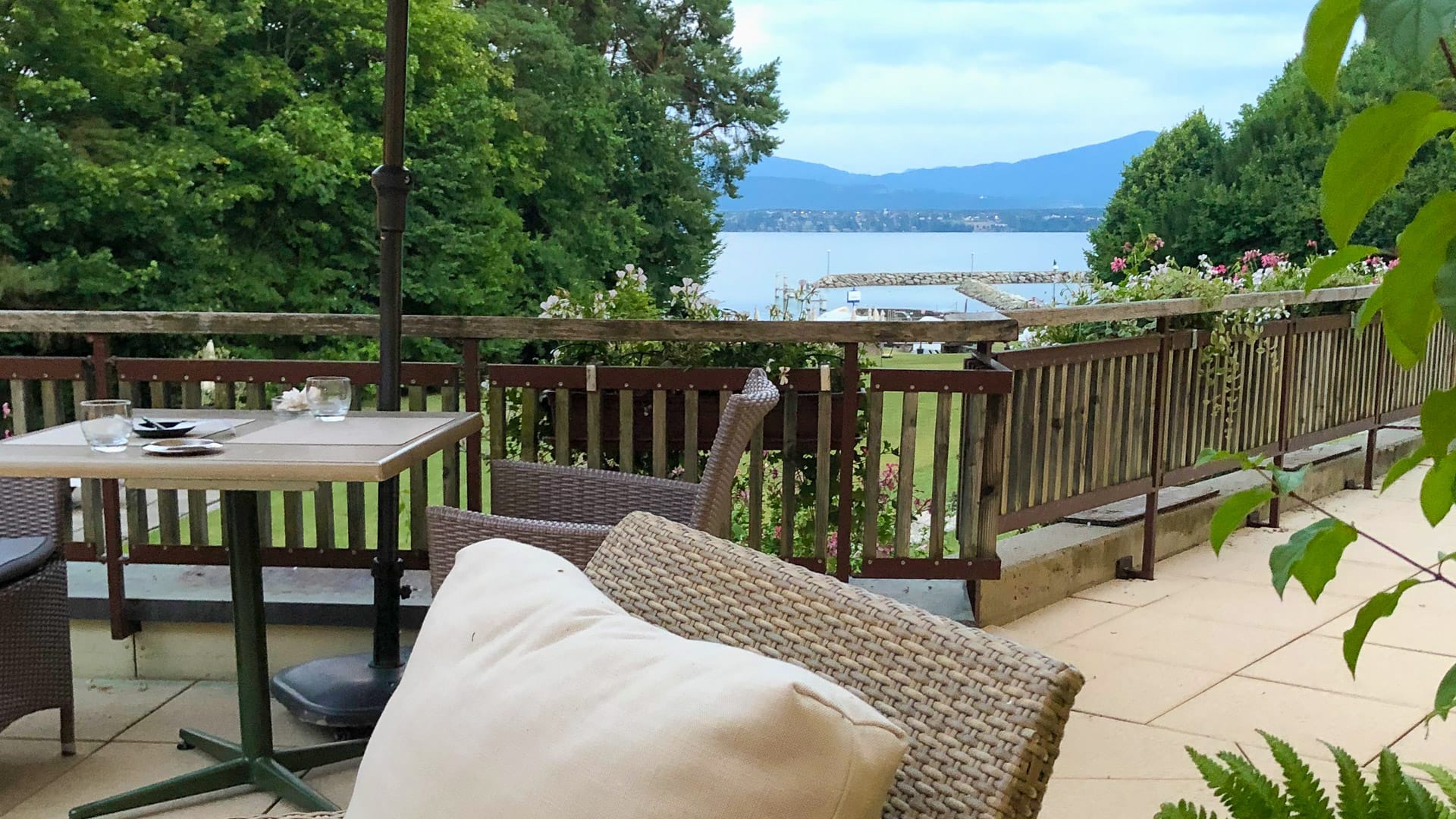 Terrace with wicker chairs and lake view at a restaurant near Lake Geneva along the Tour du Lac Léman cycle route