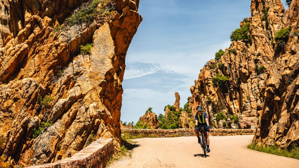 Cyclist pedalling through dramatic orange rock formations