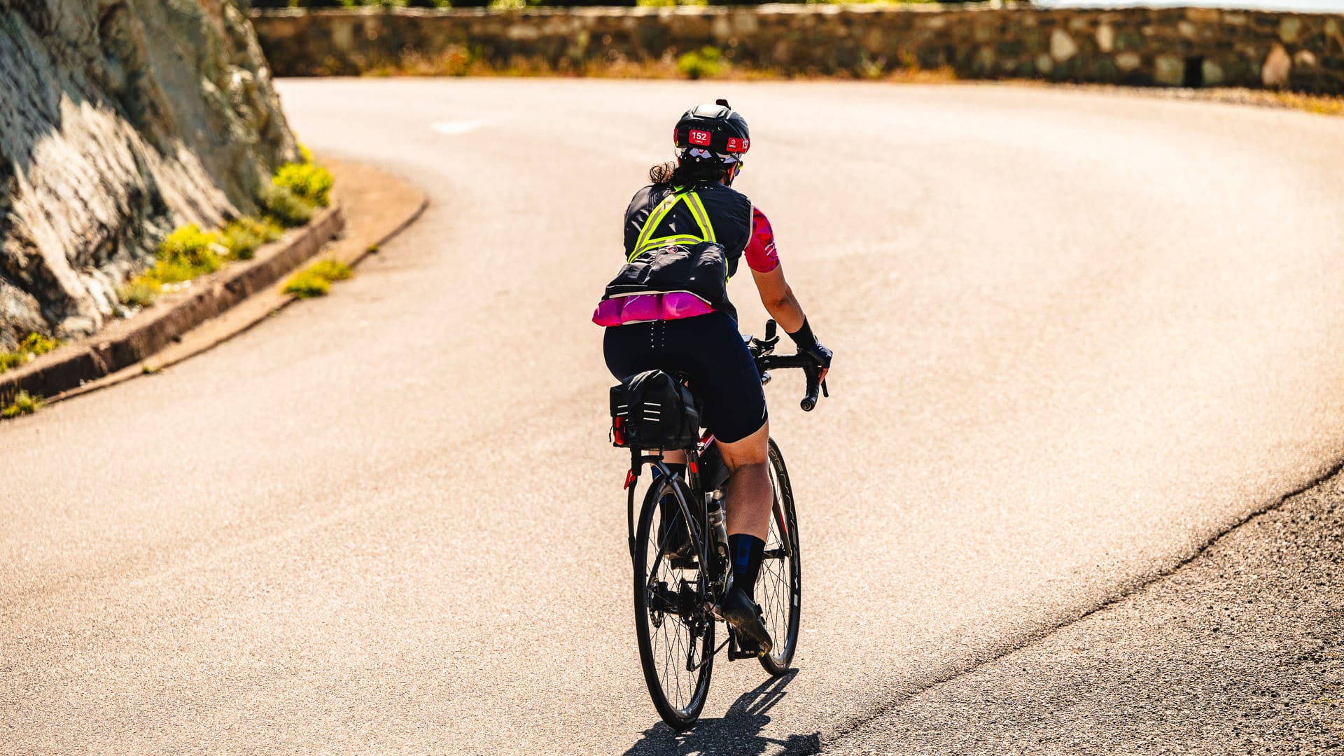 Cyclist climbing a winding mountain road in bright sun