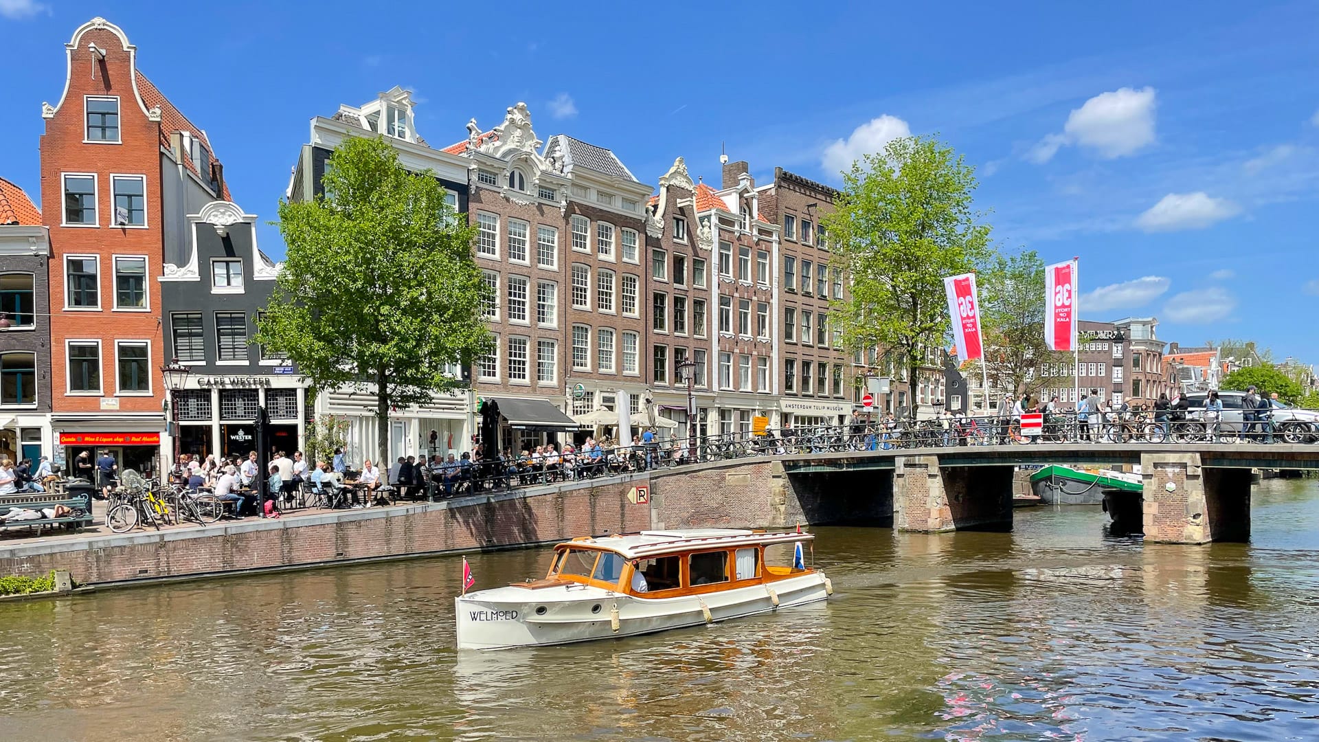 Busy Amsterdam canal on the Amsterdam to Bruges cycling route, tour boat and canal houses